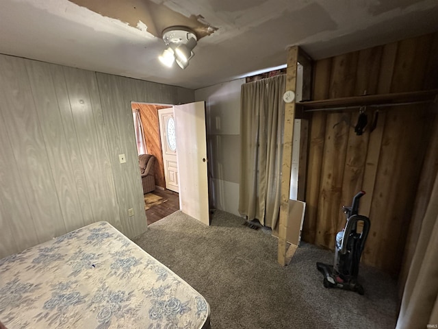 carpeted bedroom featuring ceiling fan, wooden walls, and a closet