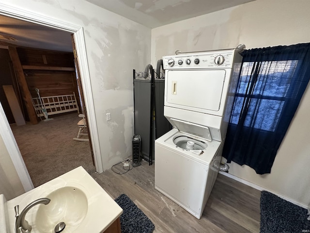 laundry area featuring stacked washer and dryer, hardwood / wood-style flooring, and sink