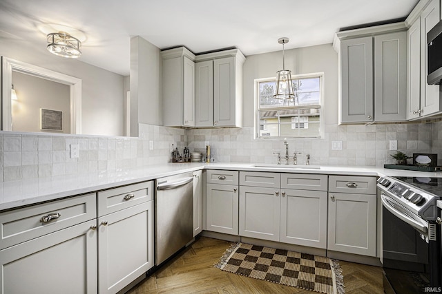 kitchen featuring appliances with stainless steel finishes, sink, gray cabinetry, backsplash, and light parquet floors