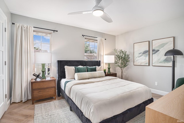 bedroom featuring multiple windows, light parquet flooring, and ceiling fan