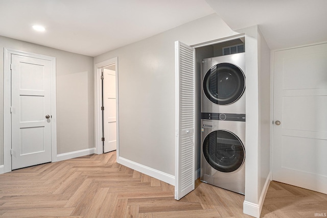 washroom with light parquet floors and stacked washer / drying machine