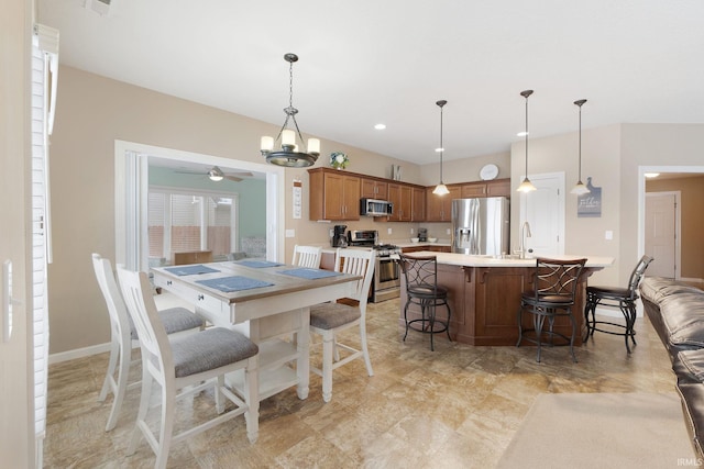 dining area with sink and ceiling fan with notable chandelier