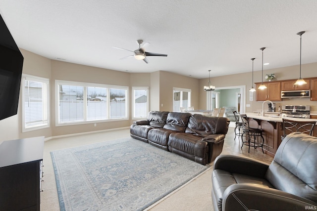 carpeted living room featuring sink, ceiling fan with notable chandelier, and a textured ceiling