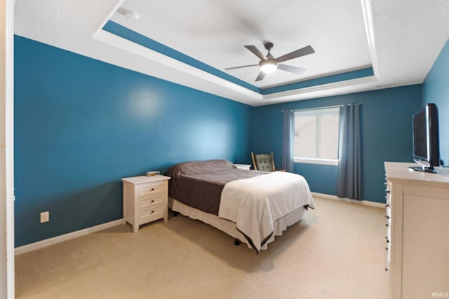 bedroom featuring light carpet, a raised ceiling, and ceiling fan