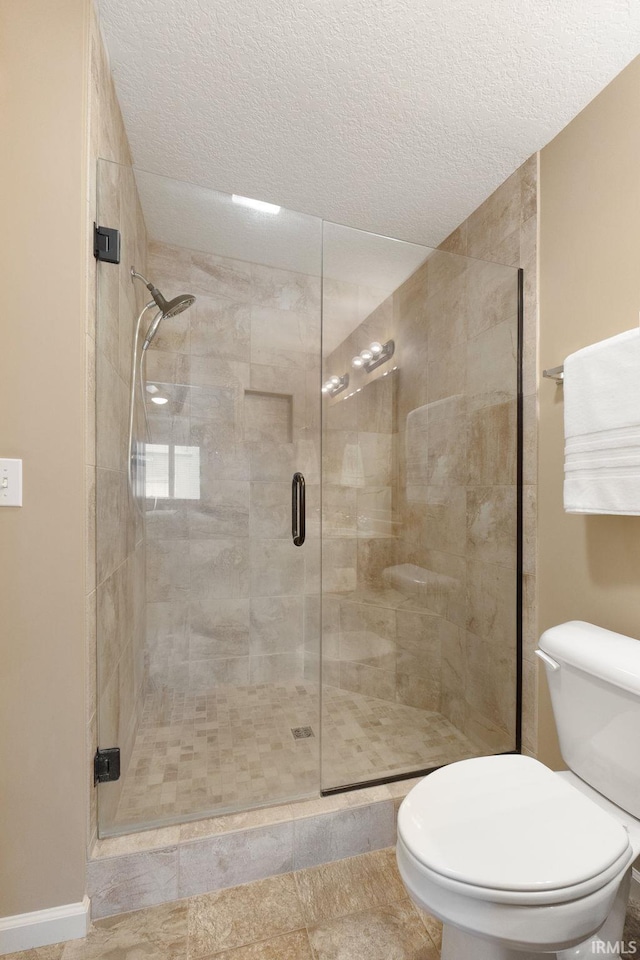 bathroom featuring an enclosed shower, a textured ceiling, and toilet