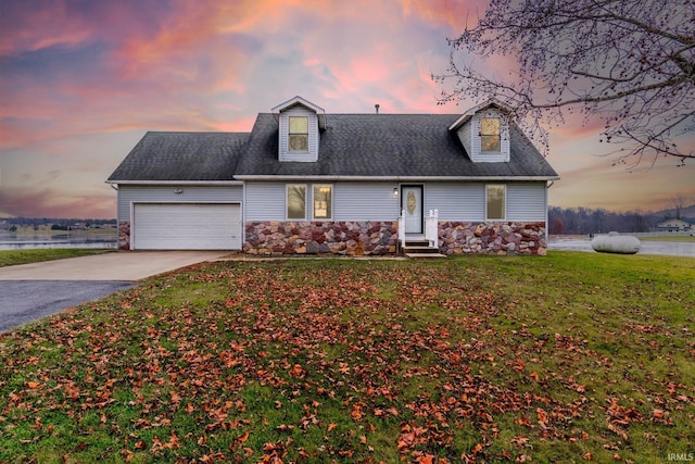 new england style home featuring a water view, a garage, and a yard