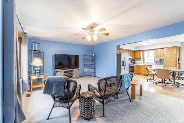 living room with ceiling fan, sink, a textured ceiling, and light hardwood / wood-style flooring