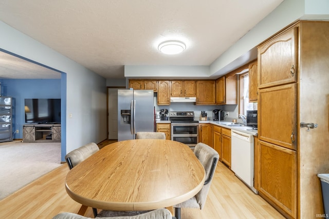 kitchen with appliances with stainless steel finishes, sink, and light hardwood / wood-style flooring