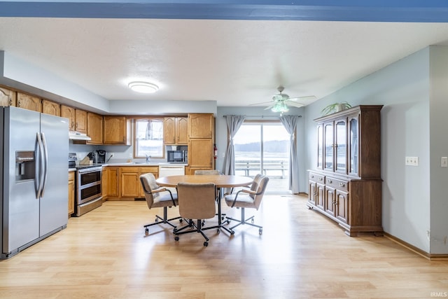 kitchen with stainless steel appliances, sink, light hardwood / wood-style floors, and a breakfast bar area