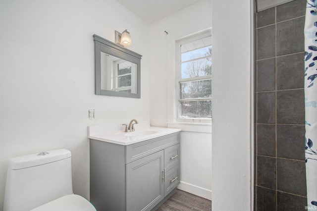 bathroom with vanity, wood finished floors, baseboards, curtained shower, and toilet