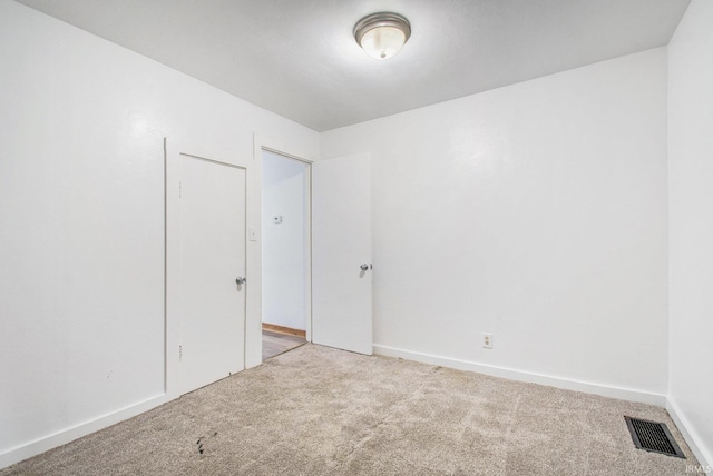 empty room featuring visible vents, carpet flooring, and baseboards