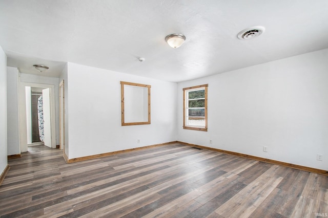 spare room with visible vents, baseboards, and wood finished floors