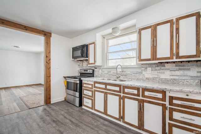 kitchen featuring dark wood-type flooring, a sink, backsplash, stainless steel range with electric cooktop, and black microwave