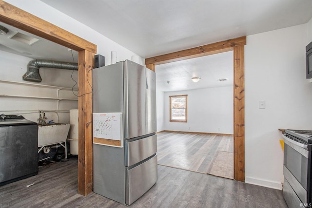 kitchen featuring baseboards, washer / clothes dryer, appliances with stainless steel finishes, and wood finished floors