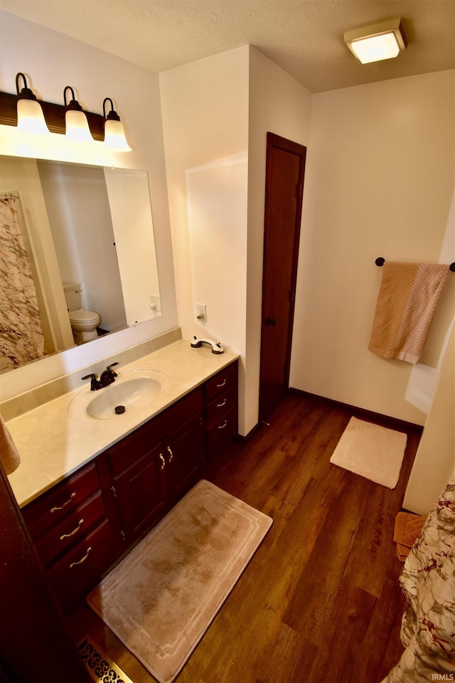 bathroom featuring hardwood / wood-style flooring, vanity, a textured ceiling, and toilet