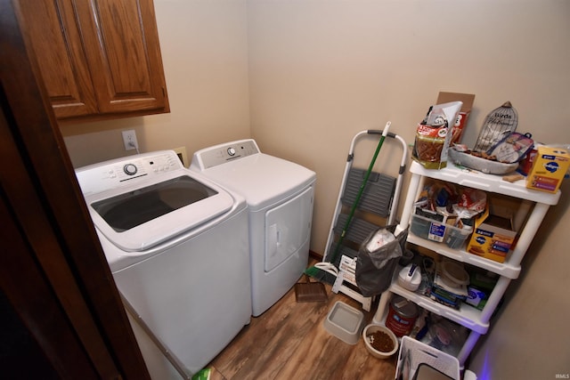 laundry room with cabinets, wood-type flooring, and washer and clothes dryer