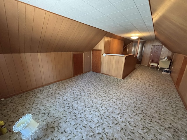 additional living space featuring vaulted ceiling and wood walls