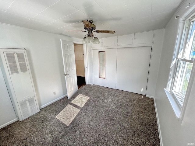 unfurnished bedroom featuring dark colored carpet, ceiling fan, and a closet