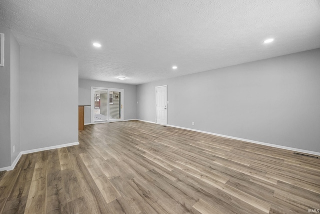 spare room featuring light hardwood / wood-style floors and a textured ceiling