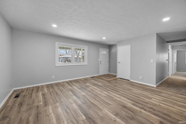 spare room featuring light wood-type flooring and a textured ceiling