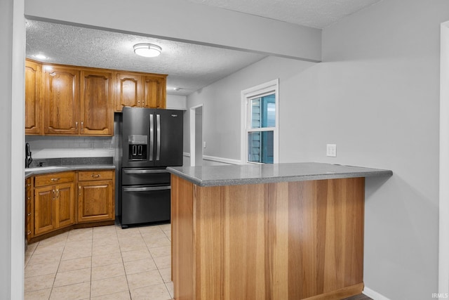 kitchen featuring light tile patterned floors, refrigerator with ice dispenser, a textured ceiling, and kitchen peninsula