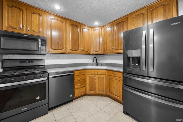 kitchen with sink, stainless steel appliances, a textured ceiling, and light tile patterned flooring