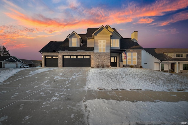 view of front of home featuring driveway, stone siding, and an attached garage