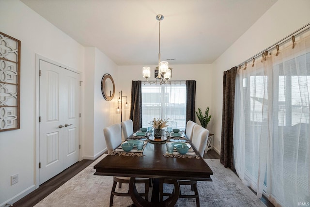 dining space with baseboards, dark wood finished floors, and a notable chandelier