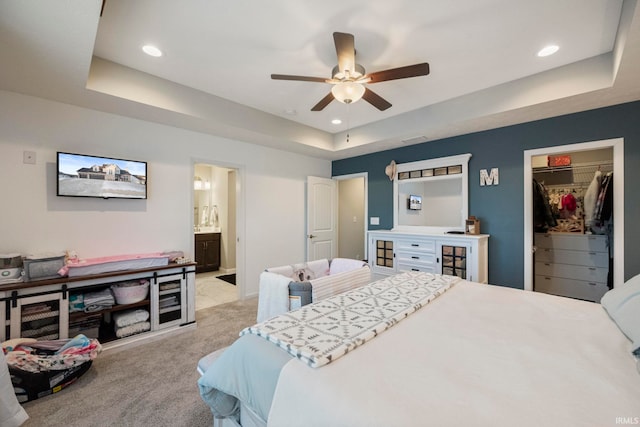 bedroom with light carpet, a spacious closet, a tray ceiling, and recessed lighting