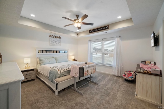 bedroom with a raised ceiling, dark carpet, baseboards, and ceiling fan