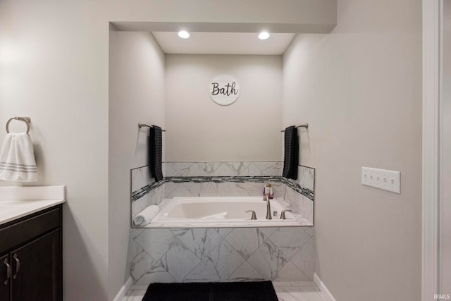 full bath featuring marble finish floor, a garden tub, vanity, and baseboards