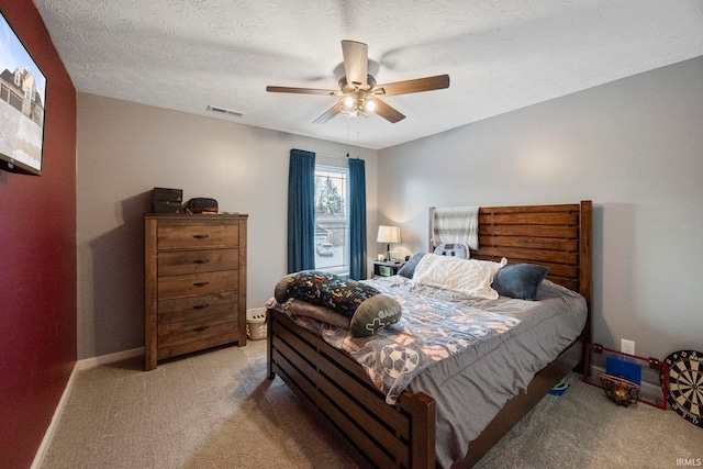 bedroom featuring light carpet, visible vents, baseboards, ceiling fan, and a textured ceiling