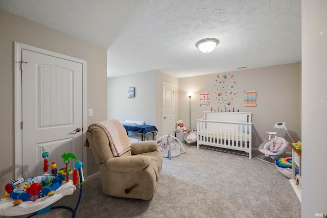 bedroom featuring a nursery area, a textured ceiling, and carpet flooring