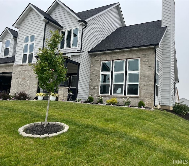 view of front of home featuring brick siding, a chimney, and a front lawn