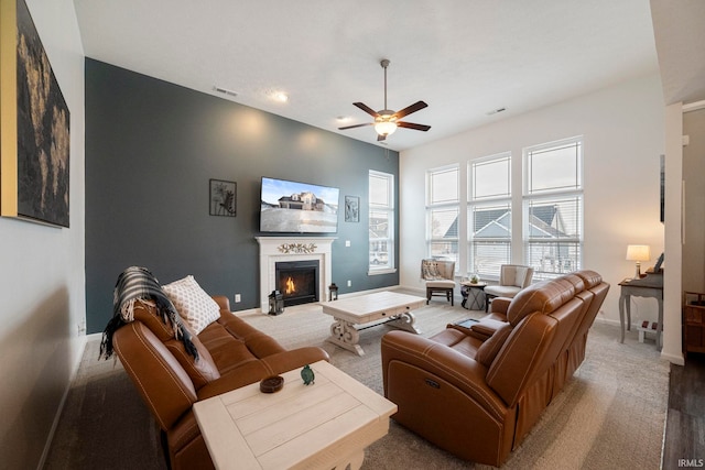 living room featuring baseboards, visible vents, ceiling fan, and a glass covered fireplace