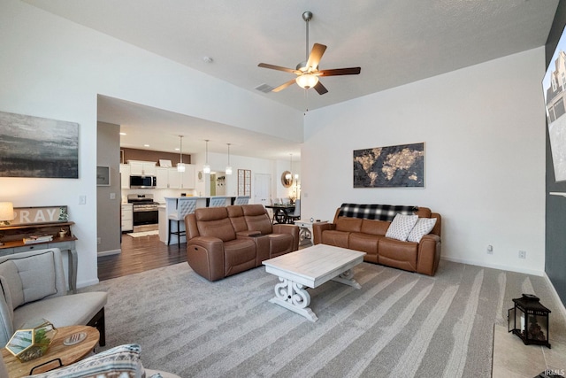 living room with light carpet, visible vents, baseboards, and ceiling fan with notable chandelier