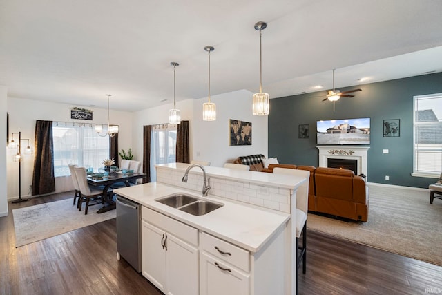 kitchen featuring a center island with sink, open floor plan, light countertops, white cabinetry, and a sink