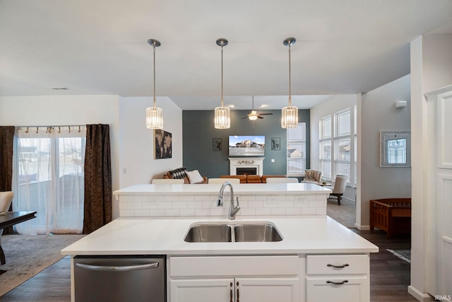 kitchen featuring white cabinets, dishwasher, open floor plan, light countertops, and a sink