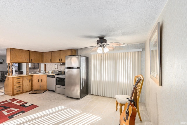 kitchen featuring light tile patterned flooring, appliances with stainless steel finishes, sink, ceiling fan, and a textured ceiling