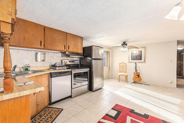 kitchen featuring sink, light tile patterned floors, appliances with stainless steel finishes, ceiling fan, and decorative backsplash