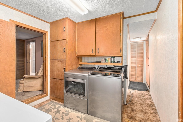 laundry area with crown molding, cabinets, a textured ceiling, and washing machine and clothes dryer