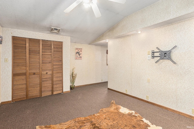 unfurnished bedroom with lofted ceiling, dark carpet, a closet, and ceiling fan