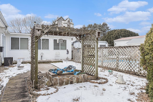 snow covered back of property featuring a pergola