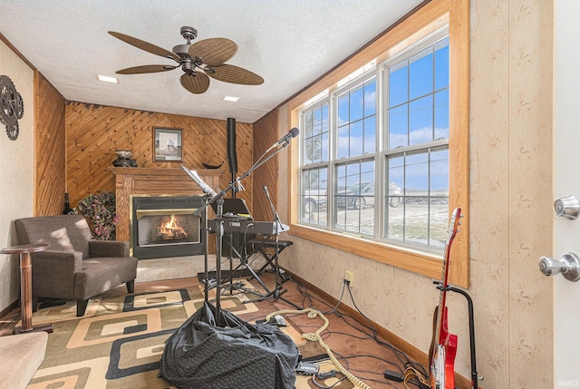 sitting room featuring ceiling fan, carpet flooring, a textured ceiling, and wooden walls