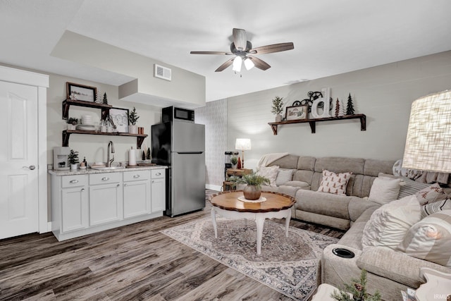 living room with dark wood-type flooring, ceiling fan, and indoor wet bar