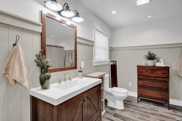 bathroom featuring hardwood / wood-style floors, wooden walls, vanity, toilet, and walk in shower