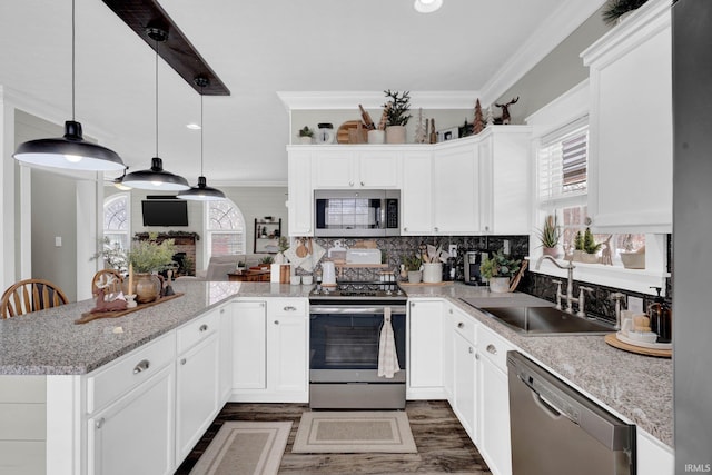 kitchen with stainless steel appliances, sink, pendant lighting, and white cabinets