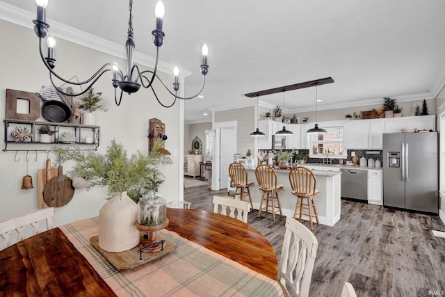 dining space with ornamental molding, light hardwood / wood-style floors, and a chandelier