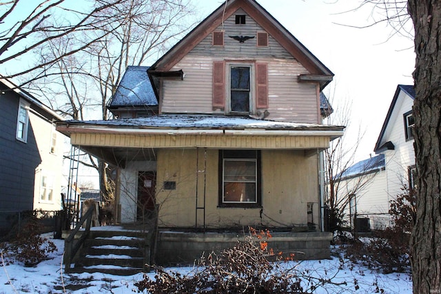 snow covered rear of property featuring covered porch