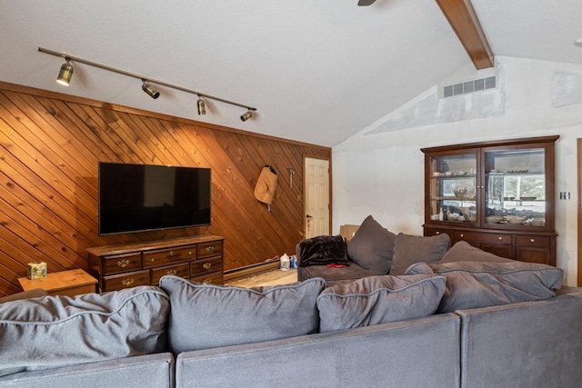 living room featuring lofted ceiling with beams, a textured ceiling, and wood walls